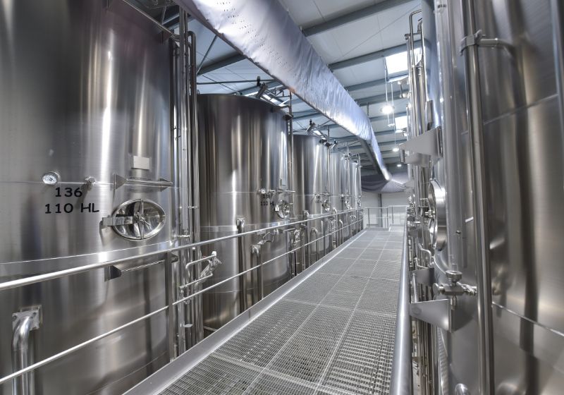 Large silver tanks with a metal grated walkway in between them.