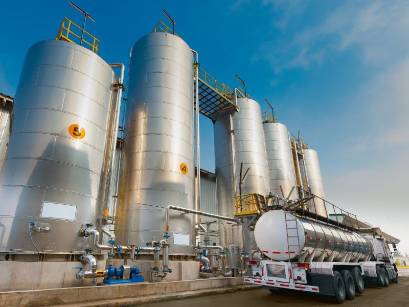 A semi-truck next to tall thin silos.