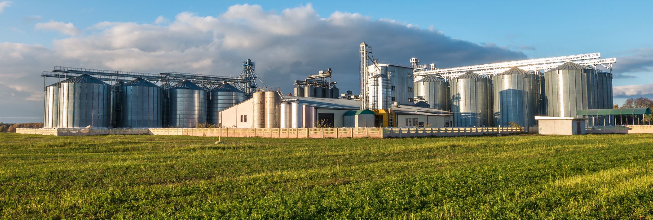 A factory with silos next to a field.