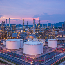 A large factory in the mountains with a purple and pink sky.